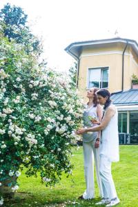 dos mujeres de pie delante de un arbusto de flores en Villa La Maggiorana, en Rivoli