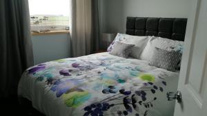 a bed with a colorful comforter and a window at The Fisherman's Snug self catering North Uist in Paible