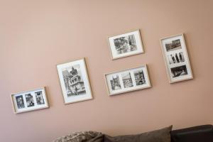 a row of pictures on a pink wall with a couch at BpR Deco Relic Studio in Budapest