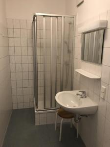 uma casa de banho branca com um chuveiro e um lavatório. em Jugendherberge Göttingen em Göttingen