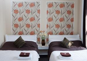 a bedroom with two beds and a wallpaper with orange flowers at Hotel 261 in London