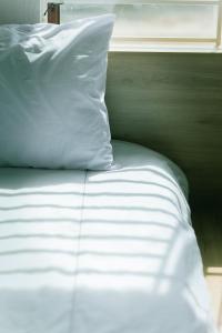 un letto con lenzuola bianche e un cuscino bianco di Tùng Homestay a Hue