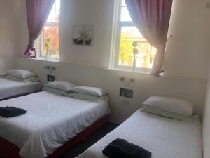 twee bedden in een kamer met twee ramen bij Bentleys in Newcastle upon Tyne