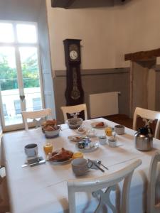une table blanche avec de la nourriture et une horloge dans l'établissement Château de la Grand'cour, à Grandchamp-des-Fontaines