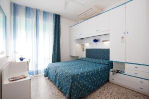 um quarto com uma cama azul e uma janela em Hotel Sanremo em Caorle