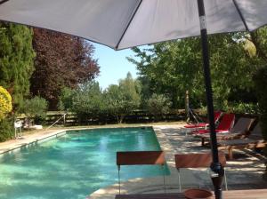an umbrella and chairs next to a swimming pool at La Jacquemarie in Monteux