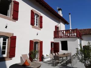 a white building with red shutters and a table and chairs at Chalbonia in Louhossoa