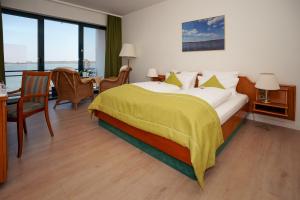 a bedroom with a large bed with a yellow blanket at Seehotel Berlin-Rangsdorf in Rangsdorf