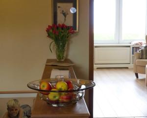 eine Schale Obst auf einem Tisch mit einer Vase Blumen in der Unterkunft Gästehaus Friedeburg in Rantum