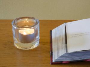 eine Kerze in einem Glas neben einem Buch in der Unterkunft Gästehaus Friedeburg in Rantum