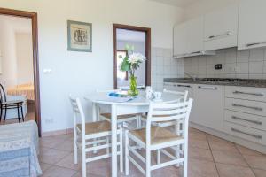 cocina con mesa blanca y sillas en Residence Villa Franca, en Capoliveri