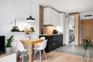 a kitchen with a wooden table and white chairs at Garden Apartments by LoftAffair in Krakow