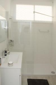 a white bathroom with a shower and a sink at Casa do Relógio in Lousã