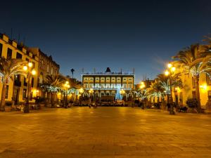 une place de ville la nuit avec un grand bâtiment dans l'établissement Columbus Rooftop Hostel, à Las Palmas de Gran Canaria