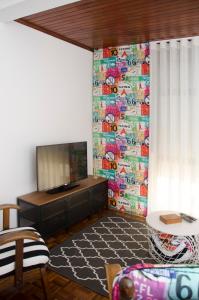 a living room with a tv and a wall with a mural at Casa do Relógio in Lousã