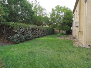 a yard with a hedge next to a house at Il Casale Delle Rose in Caltagirone