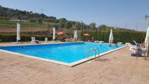 a swimming pool in a resort with people and umbrellas at Il Casale Delle Rose in Caltagirone