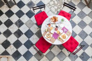 Le Ryad Boutique Hôtel في مارسيليا: طاولة مع كراسي حمراء وصحن من الطعام