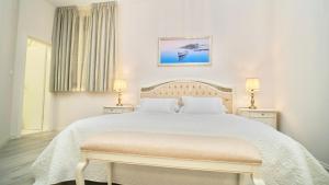 a white bedroom with a large bed and two lamps at Hotel Bellevue Trogir in Trogir