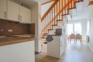 a kitchen with white cabinets and a staircase with chairs at Buedlfarm-Sperlings-Lust in Sahrensdorf