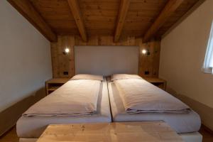two beds in a room with wooden ceilings at Appartamenti La Munt in Badia