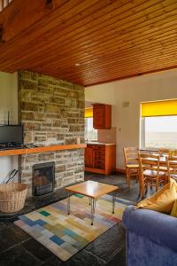 a living room with a stone fireplace and a table at Butterfly Cottage in Achill