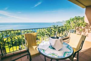 a table and chairs on a balcony with the ocean at Capo Dei Greci Taormina Coast Hotel & SPA in Santa Margherita-Sant'Alessio Siculo