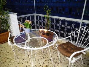 Athena's Home, Sunny Balkony 100m from metro! في أثينا: طاولة زجاجية وكراسي على شرفة