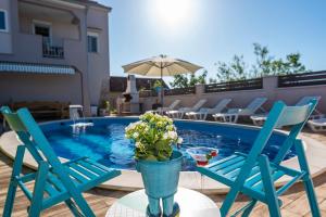 twee blauwe stoelen en een vaas met bloemen op een tafel bij een zwembad bij Villa Toni - Adriatic Luxury Villas in Zadar