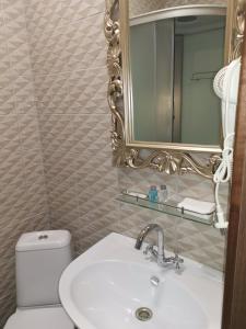 a bathroom with a sink and a mirror and a toilet at Central Hotel in Kurgan