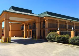 ein großes Gebäude mit einem Parkplatz davor in der Unterkunft Americas Best Value Inn Denham Springs in Denham Springs