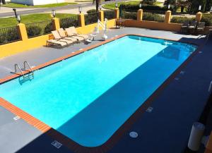 a large blue swimming pool with chairs around it at Americas Best Value Inn Denham Springs in Denham Springs