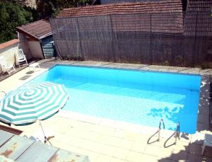 a blue swimming pool with an umbrella and an umbrella at Logis L'Auberge Bourbonnaise - Vichy sud in Saint-Yorre