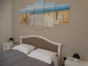 ポルト・チェザーレオにあるRelax Affittacamereのベッドルーム1室(ビーチのキャンバス4枚、ベッド1台付)