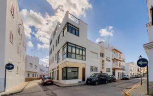 un edificio blanco con coches aparcados en una calle en Apartamentos Villas Flamenco Rentals, en Conil de la Frontera