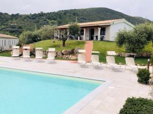 a pool with chairs and a table and a house at Agriturismo La Rocca Manna in San Teodoro