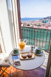 a table with a glass of orange juice and cookies on a balcony at NapoliCentro Mare - Sea View Rooms & Suites in Naples