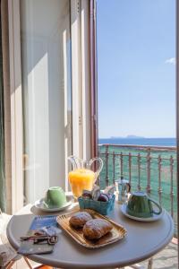 un tavolo con un bicchiere di succo d'arancia e alcuni dolci di NapoliCentro Mare - Sea View Rooms & Suites a Napoli
