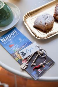 a table with a book and keys and a magazine at NapoliCentro Mare - Sea View Rooms & Suites in Naples