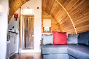 a living room with a blue couch with a red pillow at Wensleydale Glamping Pods in Redmire +32 photos