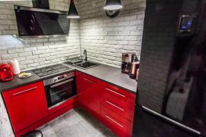 a kitchen with red cabinets and a sink at Apartament LUX in Karpacz