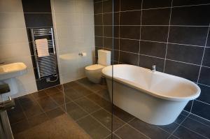 柯比朗斯代爾的住宿－Contemporary Barn Conversion in Stunning Setting，浴室配有卫生间、浴缸和水槽。