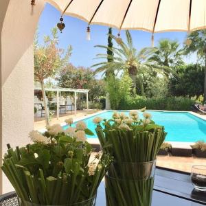 two vases with flowers on a table next to a pool at Quinta da Lua in Tavira