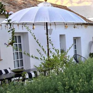 a white house with a table and an umbrella at Quinta da Lua in Tavira