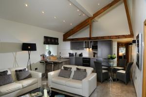 a living room with white furniture and a kitchen at Contemporary Barn Conversion in Stunning Setting in Kirkby Lonsdale