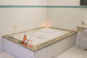 a bath tub in a white tiled bathroom at MOTEL SHAMPOO (Adult Only) in Brusque