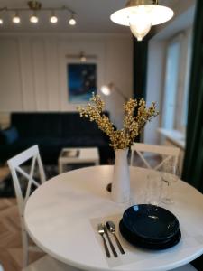 una mesa blanca con un plato y un jarrón con flores en Cosy center Apartment, en Klaipėda