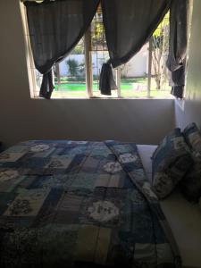 a bed with a quilt sitting in front of a window at GM Guest House in Sasolburg Town in Sasolburg