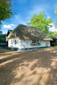 ein großes weißes Haus mit einem Strohdach in der Unterkunft Bakhuisje op de Veluwe in Heerde