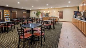 a restaurant with tables and chairs and a kitchen at Best Western Pine Springs Inn in Ruidoso Downs